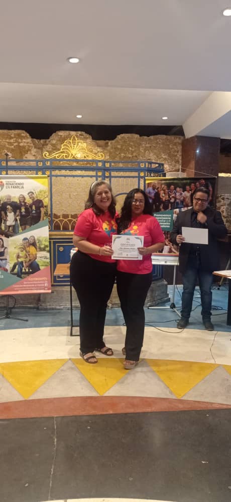 man wearing a black jacket, white shirt, blue jeans, and brown boots, playing a white electric guitar while sitting on an amp